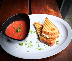 A grilled cheese on sourdough beside a bowl of tomato soup