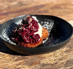 Fried pineapple topped with wild berries and cream, in a black bowl